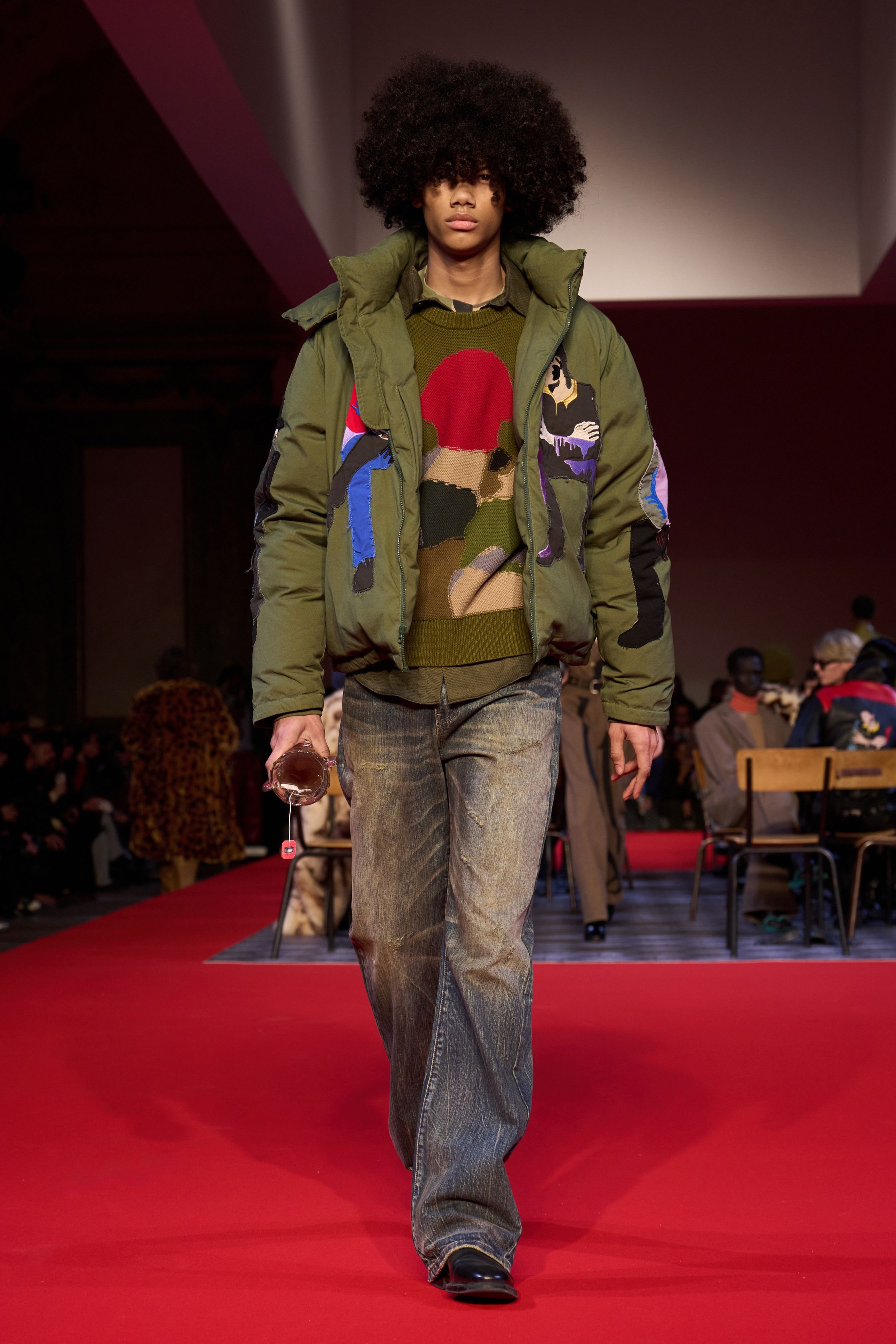 KidSuper 26FW 再次用“情绪拼贴”对抗工业化时尚秩序。手绘印花、夸张比例与情绪化色彩在红毯式秀场中被推向极致，服装不追求修饰身体，而是作为情感与记忆的载体存在。粗犷皮革、绘画感大衣与幼稚却真诚的图案语言并置，构成一种反精英、反理性的当代浪漫主义。KidSuper 依旧不完美，却极其真实-顽石频道趋势研究